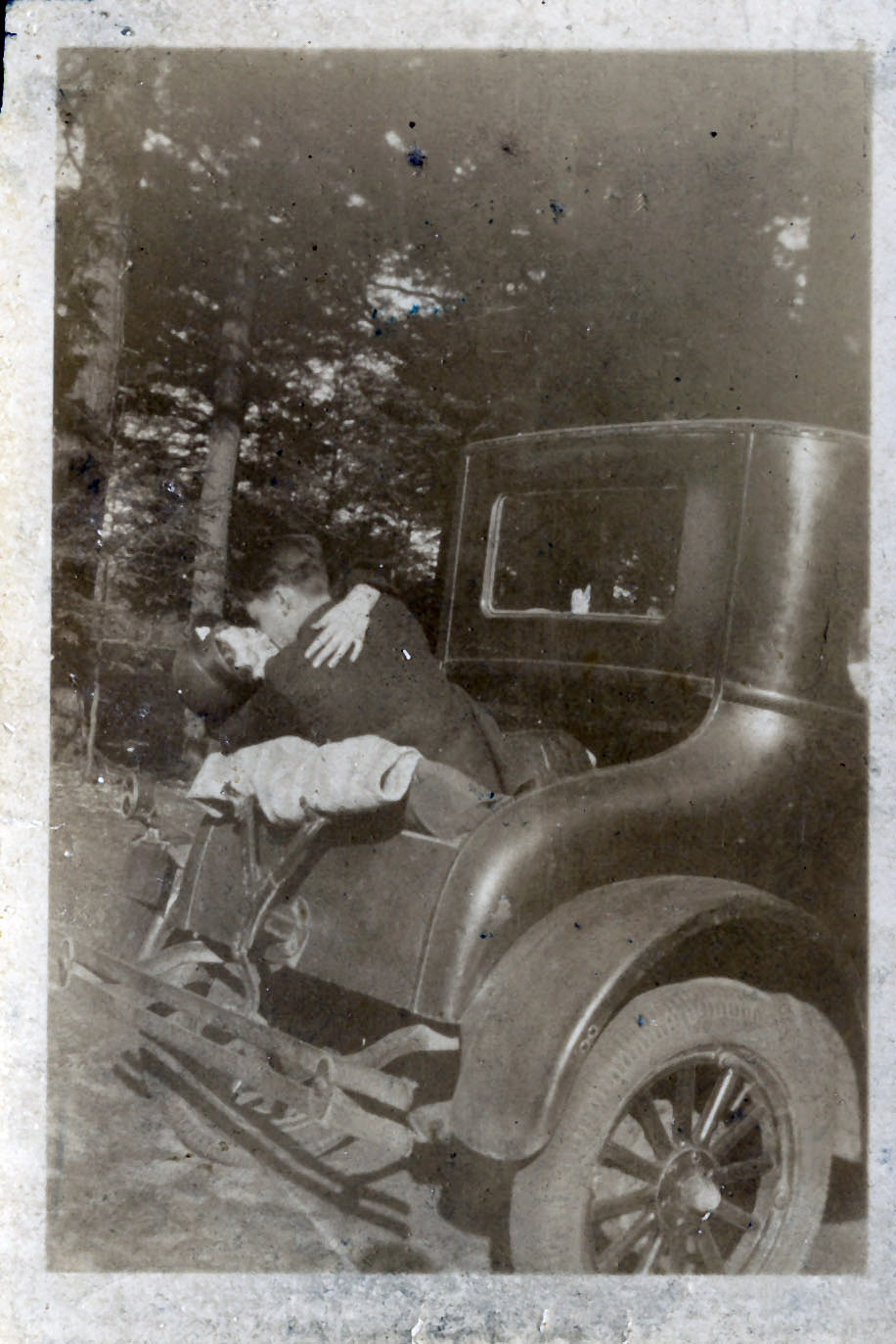 Black and white photo of man and woman kissing in Model T